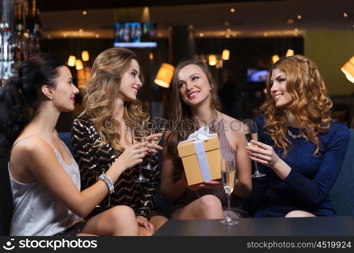 celebration, friends, bachelorette party, birthday and holidays concept - happy women with champagne glasses and gift box at night club