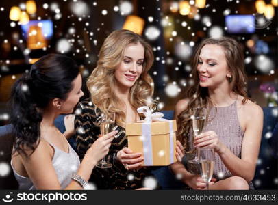 celebration, friends, bachelorette party, birthday and holidays concept - happy women with champagne glasses and gift box at night club