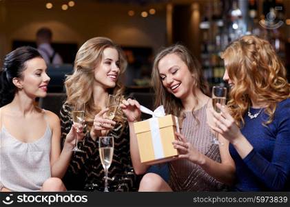 celebration, friends, bachelorette party, birthday and holidays concept - happy women with champagne glasses and gift box at night club