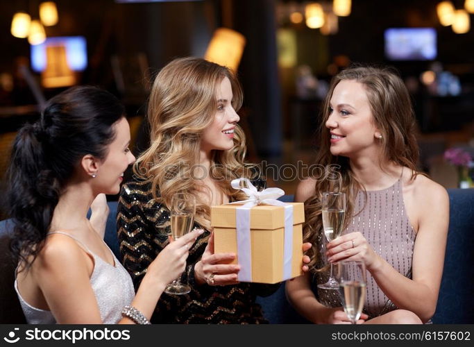 celebration, friends, bachelorette party, birthday and holidays concept - happy women with champagne glasses and gift box at night club