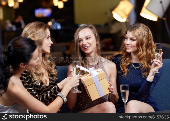 celebration, friends, bachelorette party, birthday and holidays concept - happy women with champagne glasses and gift box at night club