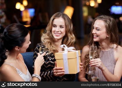 celebration, friends, bachelorette party, birthday and holidays concept - happy women with champagne glasses and gift box at night club