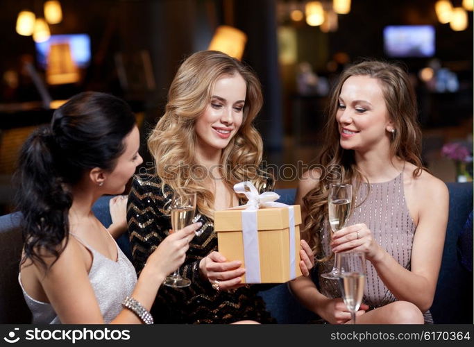 celebration, friends, bachelorette party, birthday and holidays concept - happy women with champagne glasses and gift box at night club