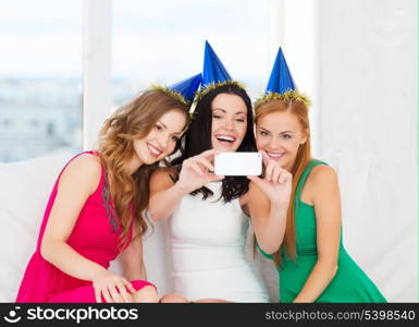 celebration, friends, bachelorette party, birthday concept - three smiling women in blue hats having fun with smartphone photo camera