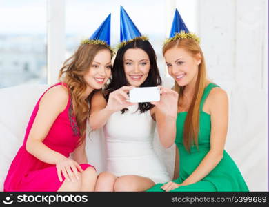 celebration, friends, bachelorette party, birthday concept - three smiling women in blue hats having fun with smartphone photo camera