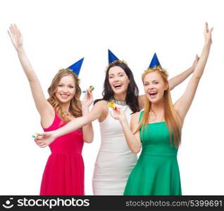 celebration, friends, bachelorette party, birthday concept - three smiling women wearing blue hats and blowing favor horns and waving hands