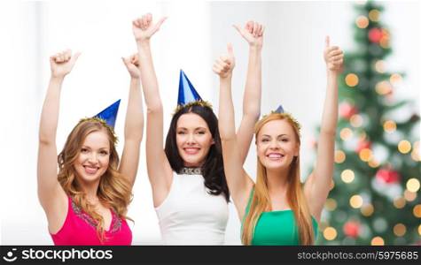 celebration, friends, bachelorette party, birthday concept - three smiling women wearing blue hats and showing thumbs up