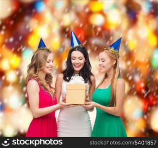celebration, friends, bachelorette party, birthday concept - three smiling women wearing blue hats with gift box