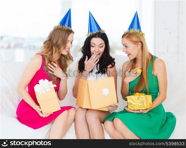 celebration, friends, bachelorette party, birthday concept - three smiling women wearing blue hats with gift boxes