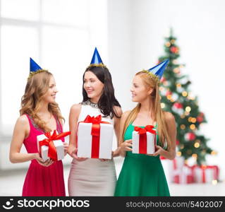 celebration, friends, bachelorette party, birthday concept - three smiling women wearing blue hats with gift boxes