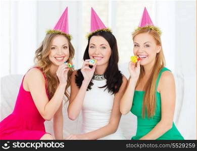 celebration, friends, bachelorette party, birthday concept - three smiling women wearing pink hats and blowing favor horns