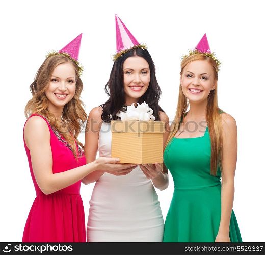 celebration, friends, bachelorette party, birthday concept - three smiling women wearing pink hats with gift box