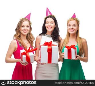 celebration, friends, bachelorette party, birthday concept - three smiling women wearing pink hats with gift boxes