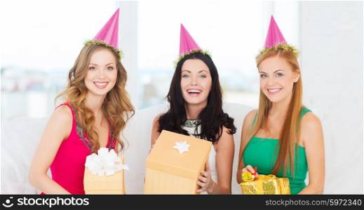 celebration, friends, bachelorette party, birthday concept - three smiling women wearing pink hats with gift boxes