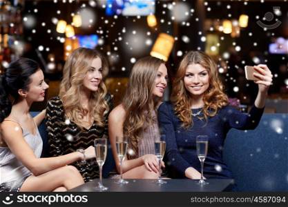 celebration, friends, bachelorette party, technology and christmas holidays concept - happy women with champagne and smartphone taking selfie at night club over snow