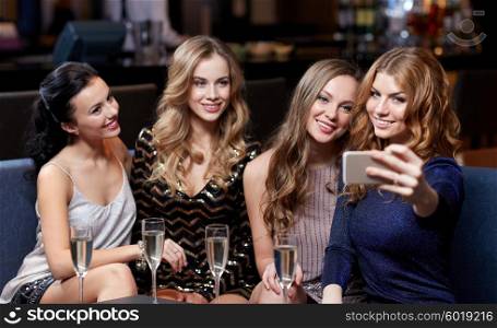 celebration, friends, bachelorette party, technology and holidays concept - happy women with champagne and smartphone taking selfie at night club