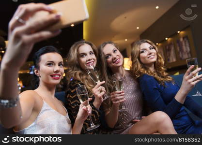 celebration, friends, bachelorette party, technology and holidays concept - happy women with champagne glasses and smartphone taking selfie at night club