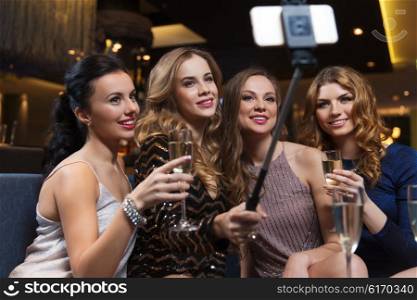 celebration, friends, bachelorette party, technology and holidays concept - happy women with champagne and smartphone selfie stick taking picture at night club