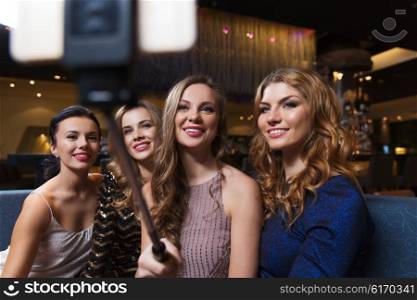 celebration, friends, bachelorette party, technology and holidays concept - happy women with smartphone selfie stick taking picture at night club
