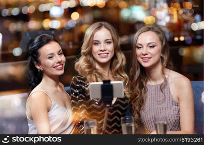 celebration, friends, bachelorette party, technology and holidays concept - happy women with champagne and smartphone selfie stick taking picture at night club