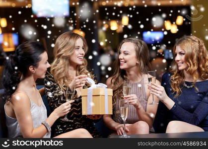 celebration, friends, new year, christmas and winter holidays concept - happy women with champagne glasses and gift box at bachelorette or birthday party at night club over snow