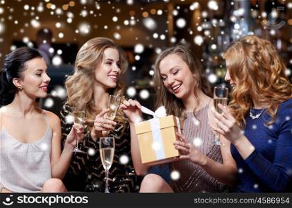celebration, friends, new year, christmas and winter holidays concept - happy women with champagne glasses and gift box at bachelorette or birthday party at night club over snow