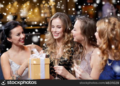celebration, friends, new year, christmas and winter holidays concept - happy women with champagne glasses and gift box at bachelorette or birthday party at night club over snow