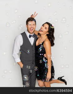 celebration, fun and holidays concept - happy couple hugging in soap bubbles at party. happy couple hugging in soap bubbles at party