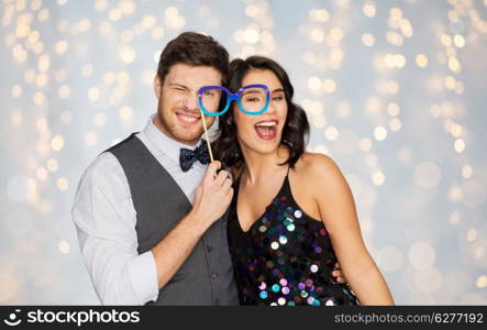 celebration, fun and holidays concept - happy couple posing with party glasses over festive lights background. happy couple with party glasses having fun. happy couple with party glasses having fun