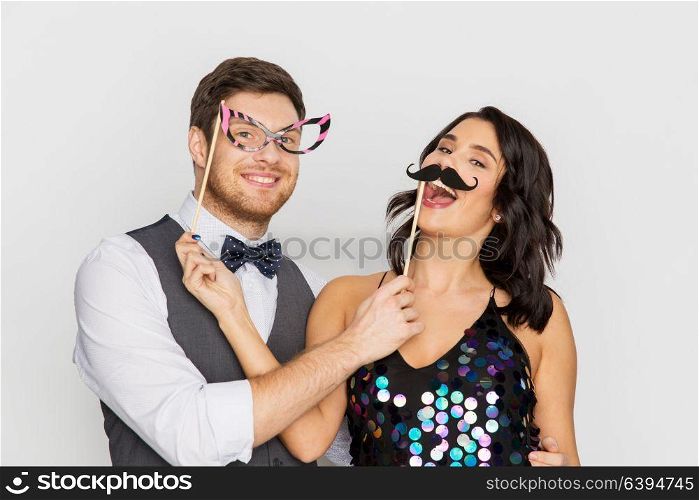 celebration, fun and holidays concept - happy couple posing with party props. happy couple with party props having fun