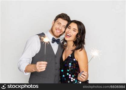 celebration, fun and holidays concept - happy couple with sparklers at party. happy couple with sparklers at party