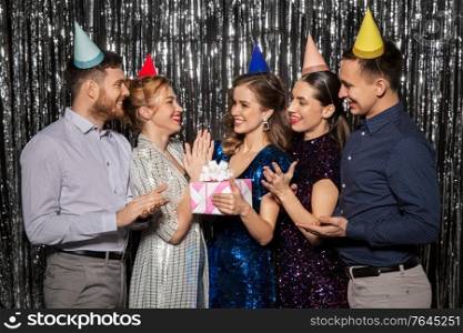 celebration, fun and holidays concept - happy friends in party hats with birthday gift applauding. happy friends in party hats with birthday gift
