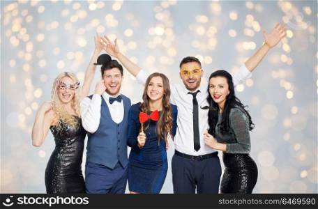 celebration, fun and holidays concept - happy friends posing with party props over festive lights background. happy friends with party props posing over lights