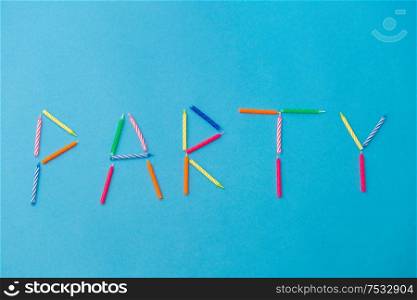 celebration, holiday and lettering concept - word party made of colorful birthday candles on blue background. word party made of birthday candles on blue