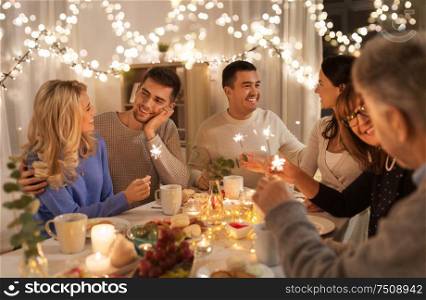 celebration, holidays and christmas concept - happy family with sparklers having fun at dinner party at home. family with sparklers having dinner party at home