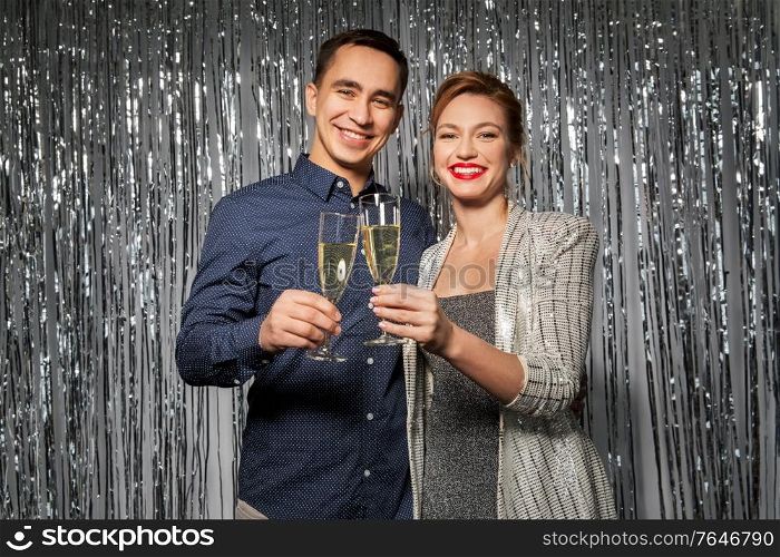 celebration, holidays and people concept - happy couple toasting champagne glasses at party. happy couple toasting champagne glasses at party