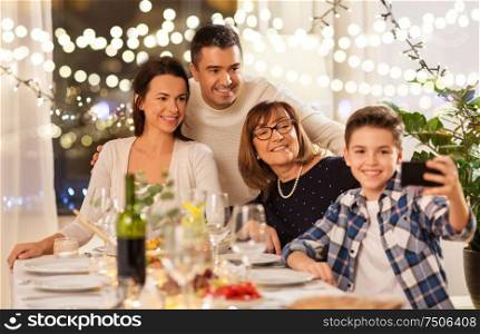 celebration, holidays and people concept - happy family having dinner party at home and taking selfie by smartphone. family having dinner party and taking selfie