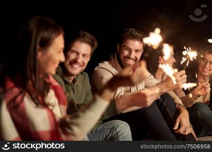 celebration, holidays and people concept - happy friends with sparklers at night outdoors. happy friends with sparklers at night outdoors