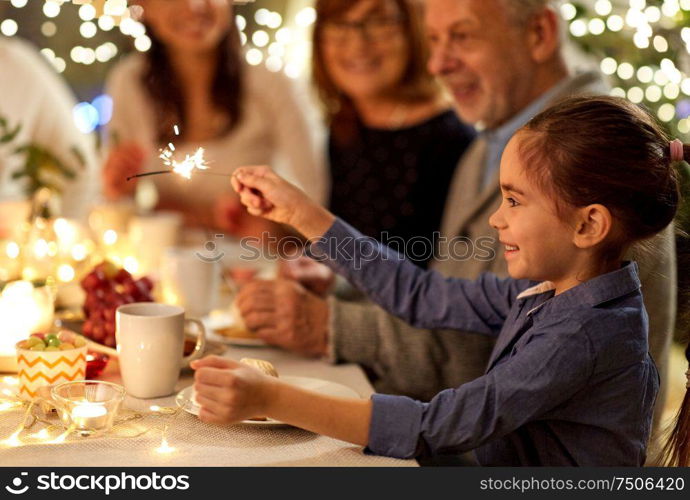 celebration, holidays and people concept - happy girl with sparkler at family tea party. happy girl with sparkler at family tea party