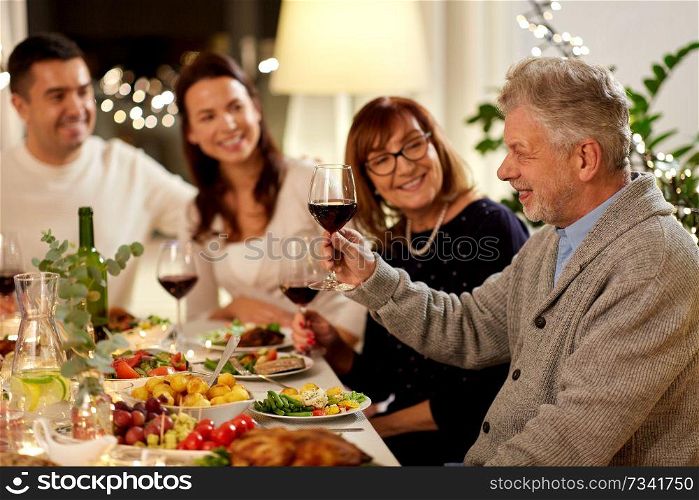 celebration, holidays and people concept - happy grandfather with glass of red wine toasting with family having dinner party at home. happy family having dinner party at home