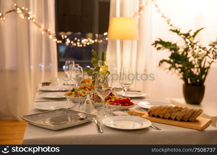 celebration, holidays, catering and eating concept - table served with plates, wine glasses and food for home dinner party. table served with plates, wine glasses and food