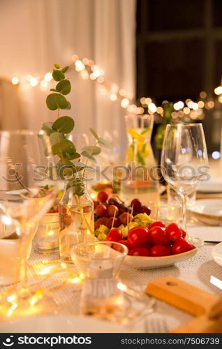 celebration, holidays, catering and eating concept - table served with plates, wine glasses and food for home dinner party. table served with plates, wine glasses and food