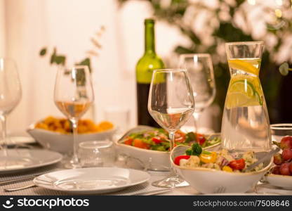 celebration, holidays, catering and eating concept - table served with plates, wine glasses and food for home dinner party. table served with plates, wine glasses and food