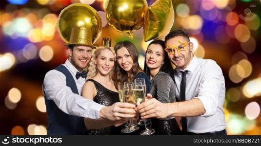 celebration, luxury and holidays concept - happy friends with golden party props clinking champagne glasses over festive lights background. happy friends clinking champagne glasses at party