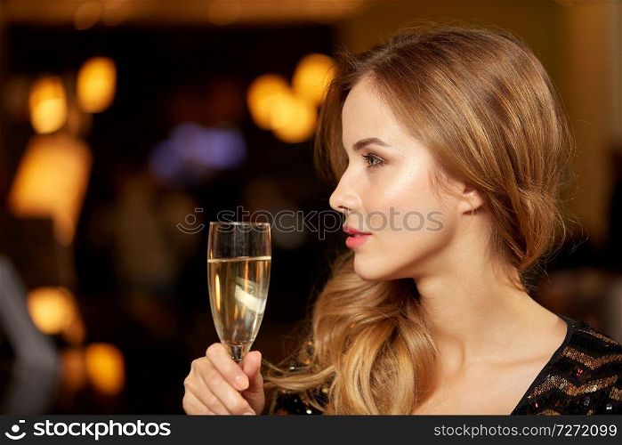 celebration, party and holidays concept - woman with glass of non-alcoholic champagne at night club. woman with glass of champagne at night club