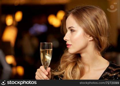 celebration, party and holidays concept - woman with glass of non-alcoholic champagne at night club. woman with glass of champagne at night club