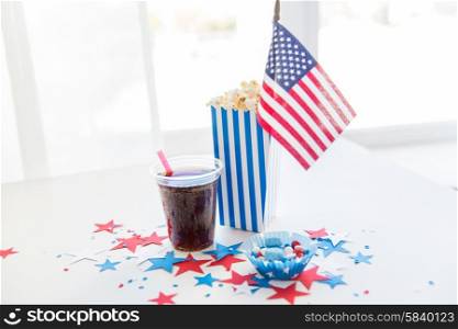 celebration, patriotism and holidays concept - close up of american flag, coca cola cup, popcorn and candies with stars confetti decoration at 4th july party on independence day