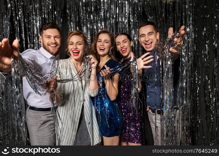 celebration, people and holiday style concept - happy friends in party clothes with tinsel fringe curtain over black background. happy friends in party clothes with tinsel curtain