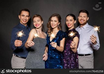 celebration, people and holiday style concept - happy friends in party clothes with sparklers over black background. happy friends in party clothes with sparklers