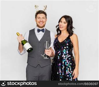 celebration, people and holidays concept - happy couple with bottle of non alcoholic champagne and wine glasses at christmas or new year party. couple with champagne bottle at christmas party